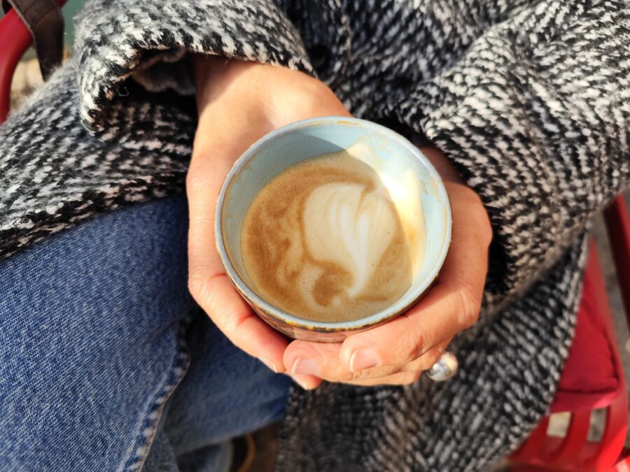 Pavlina hält einen Becher mit Cappuccino in den Händen.