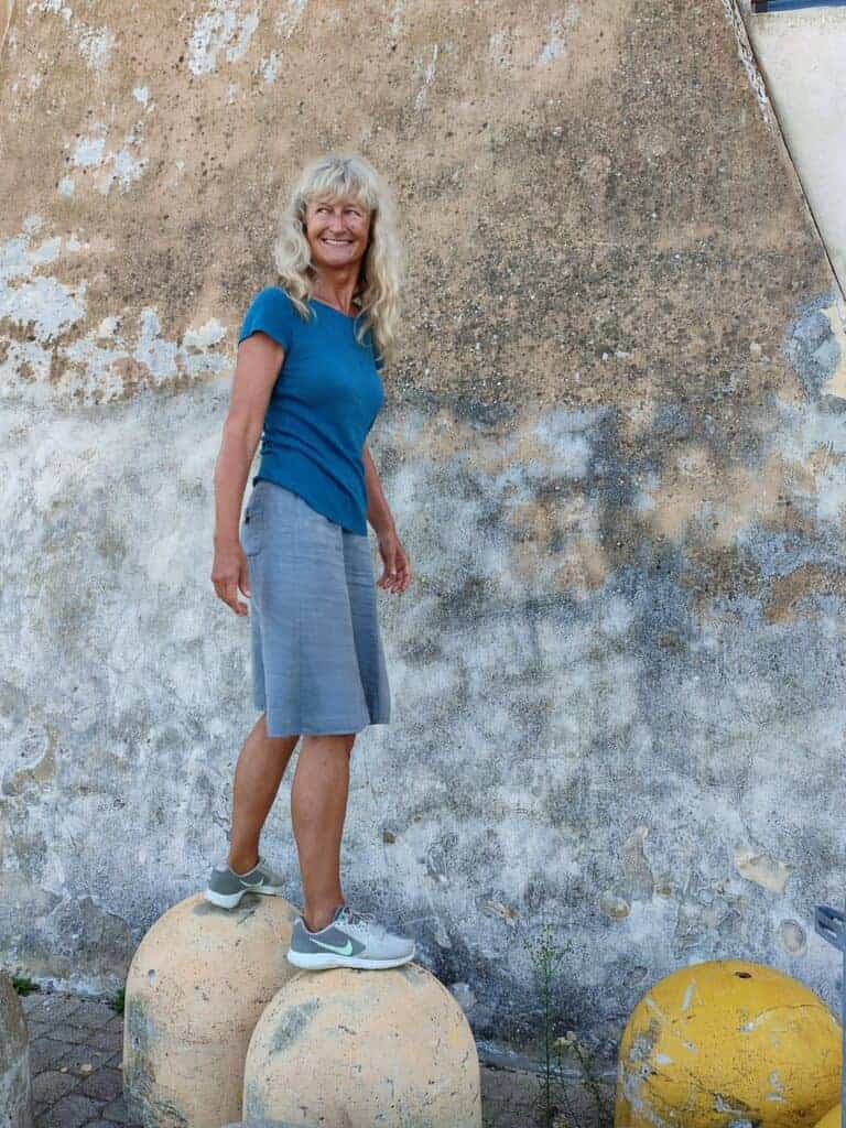 Pavlina steht lächelnd auf Betonpollern vor einer verwitterten Wand während eines persönlichen Jahresrückblicks.